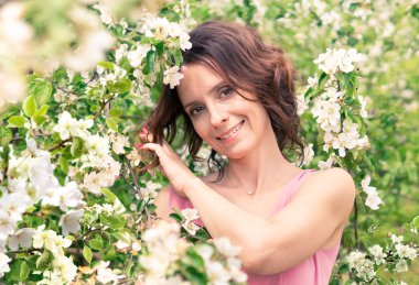 Kadın çiçek açan bir bahçede yürüyor. Koyu saçlı bir kadının portresi. Elma ağacı baharda açar.