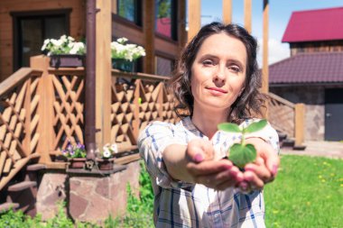 Çiçekli güzel bir kadın bahçıvan. Bir kadın evdeki bir bahçeye fidanlar ekiyor. Çiftçinin elinde lahanalar.