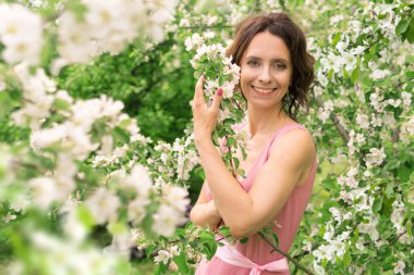 Güzel bir kadın çiçek açan bir bahçede yürüyor. Koyu saçlı bir kadının portresi. Elma ağacı baharda açar.