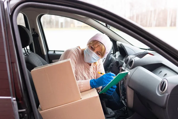 Eve teslim. Coronavirus. Kurye elinde tıbbi lastik eldivenlerle dolu bir karton kutu tutuyor. Karantina.