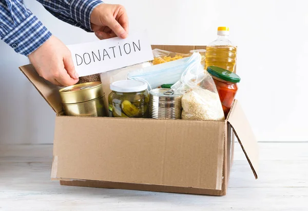 Donation box with various food. Open cardboard box with oil, canned food, cereals and pasta.