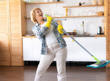 Çekici kadın evi temizliyor. Bir paspas tutar ve şarkı söyler..