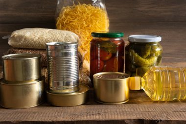 Koyu ahşap arka planda konserve yiyecek ve tahıl paketleri. Yiyecek stoku kavramı