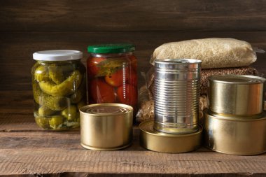 Koyu ahşap arka planda konserve yiyecek ve tahıl paketleri. Yiyecek stoku kavramı