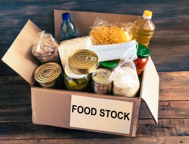 Yiyecek stoklarıyla dolu bir kutu. Tereyağlı karton kutu, konserve yiyecek, mısır gevreği ve makarna. Rezerv.