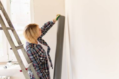 Bir kadın mimar inşaat alanını inceliyor. Orta yaşlı bir kadın bir dairede tamirat yapıyor..