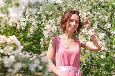 Güzel bir kadın çiçek açan bir bahçede yürüyor. Koyu saçlı bir kadının portresi. Elma ağacı baharda açar.