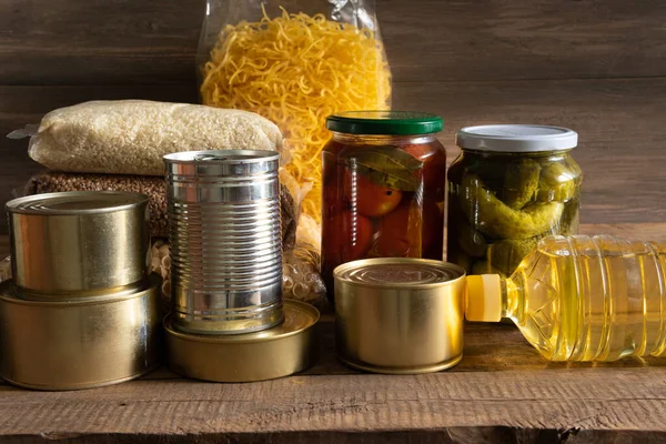 Koyu ahşap arka planda konserve yiyecek ve tahıl paketleri. Yiyecek stoku kavramı