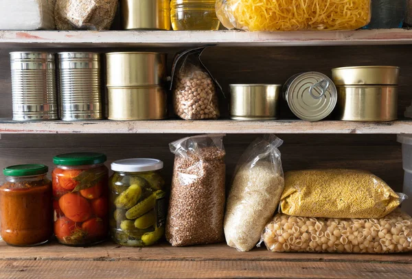 Canned vegetables, cereals and canned food on the shelves on a dark wooden background. Foodstock concept