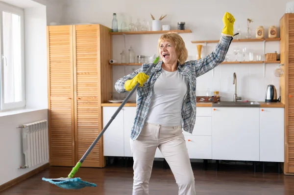 Orta yaşlı bir kadın evi temizliyor. Bir MOP tutuyor ve şarkı söylüyor..