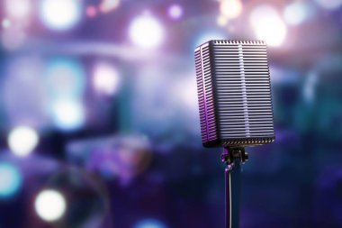 Parlak ışık lekeli bulanık bokeh 'in arka planına karşı ayakta duran bir mikrofon.