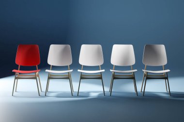 Sandalyeler stüdyoda. Kırmızı bir sandalye öne çıkıyor. Liderlik kavramı.