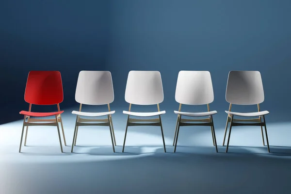 Sandalyeler stüdyoda. Kırmızı bir sandalye öne çıkıyor. Liderlik kavramı.
