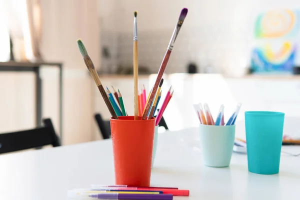 Lápis e escovas em um copo na mesa na oficina de arte — Fotografia de Stock