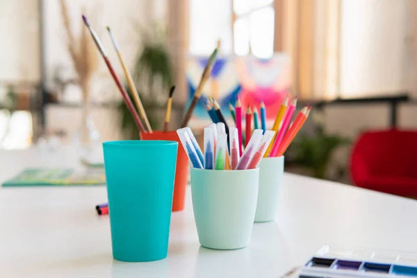 Lápices y pinceles en un vaso sobre la mesa en el taller de arte — Foto de Stock