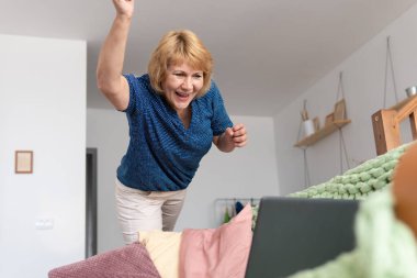 Bir kadın kanepede dizüstü bilgisayarla oturuyor..