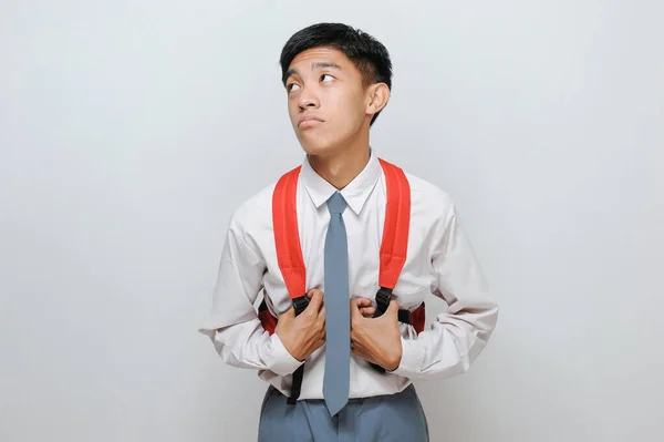 Portrait of lazy Asian high school student with uniform, isolated on grey background