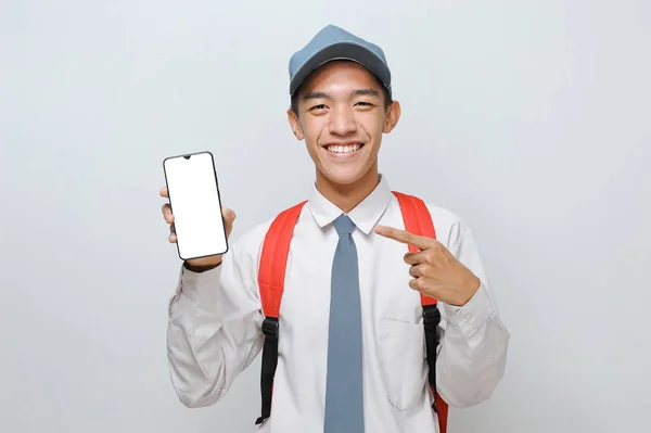 身着制服的高中生们展示着白色的手机显示屏 在灰色背景下孤立地登广告 — 图库照片