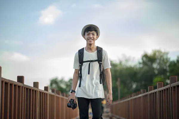 Mladý Muž Cestovatel Fotograf Úsměvem Kráčející Dřevěném Mostě Batohem Drží — Stock fotografie