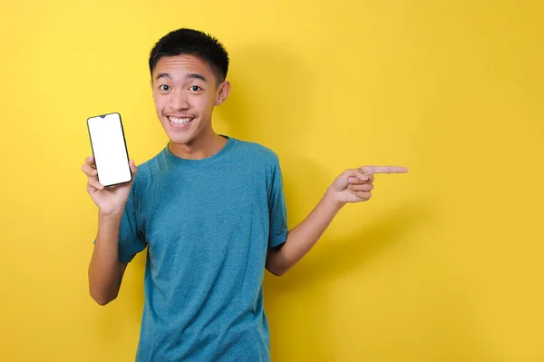 兴奋的亚洲年轻人震惊地将手机屏幕对准了复制空间 被黄色背景隔离 — 图库照片