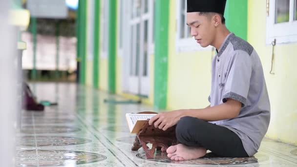 モスクでラマダーン カレームの聖クルアーンを読む若いアジア系ムスリム男性 — ストック動画