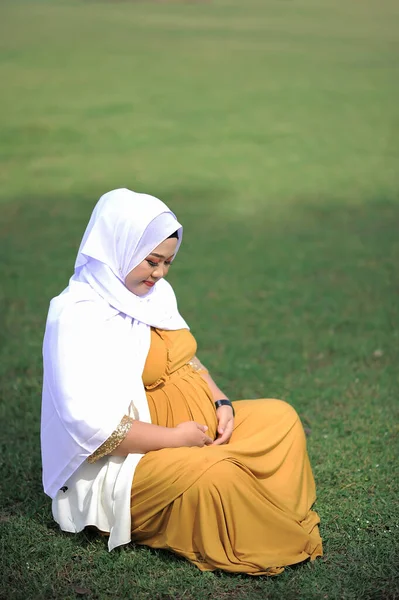 Hamile Asyalı Müslüman kadın parkta dinleniyor.