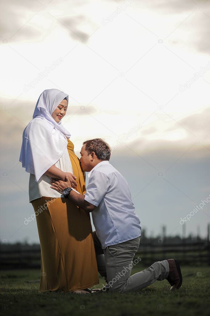 Affectionate young Asian Muslim couple in love wait for child, have positive expression, want to become parents soon. Maternity, fatherhood and pregnancy.
