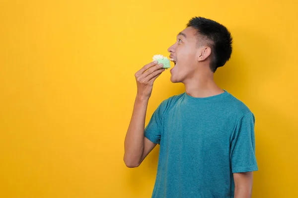 Χαρούμενος Ενθουσιασμένος Νεαρός Ασιάτης Τρώει Κέικ Απομονωμένος Κίτρινο Φόντο Φωτογραφία Αρχείου