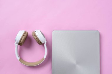 Modern kablosuz kulaklığın Top View Flatlay 'i ve pembe renk çalışma alanı üzerinde minimalist laptop