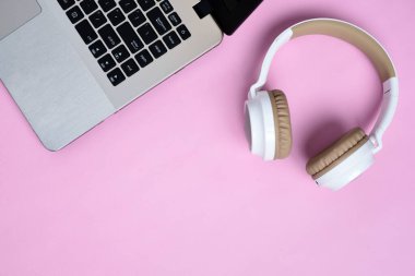 Modern kablosuz kulaklığın Top View Flatlay 'i ve pembe renk çalışma alanı üzerinde minimalist laptop