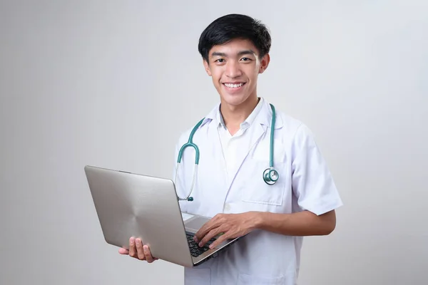 Sonriente Joven Asiático Médico Masculino Pie Trabajando Ordenador Portátil Aislado —  Fotos de Stock