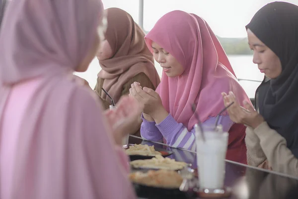 Muslim asian friends pray together when breaking fast at cafe