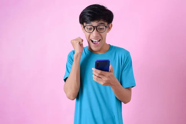 在粉色背景下 拿着一部带有复制空间的眼镜的手机的亚洲男人感到惊讶 — 图库照片