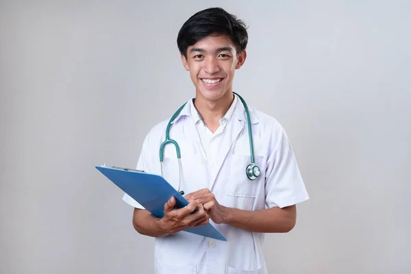 Mladý Šťastný Asijský Lékař Drží Lékařskou Kartu Nad Šedým Studiem — Stock fotografie