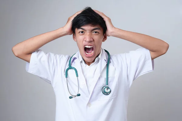 Genç Asyalı Erkek Doktor Çığlık Atıyor Kafasını Tut Gri Arka — Stok fotoğraf