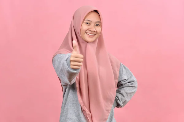 年轻的亚洲穆斯林妇女在粉色背景下大显身手 模拟复制空间 把大拇指举起来 — 图库照片