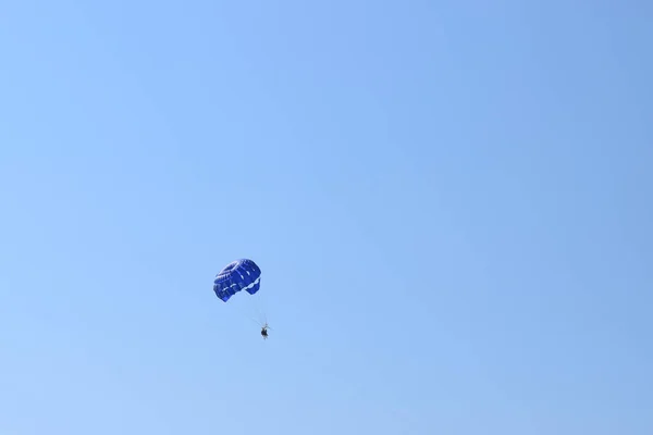 娱乐性的模仿背景 三个人在蓝色降落伞下的轮廓被拖到了一艘船后面 在地中海上空的空中滑行的三重唱 — 图库照片