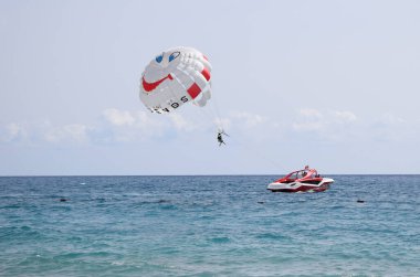 Bir tekne tarafından çekilen komik bir paraşüt kanadı. Deniz yaz tatili. Gökyüzü berrak ve bulutsuz, deniz sakin ve yüzeyde sığ bir dalga var. Tekirova, Antalya Türkiye. 27 Eylül 2020