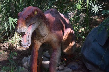 Orman parkındaki dinozor heykeli, arka plan için doğa. Türkiye 'deki Dinopark' ta Dinozor Deinonychus 'un gerçekçi bir heykeli, Goynuk. Deinonychus-Kretase 130-120 milyon yıl önce