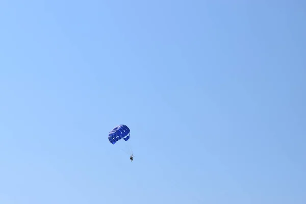 娱乐性的模仿背景 三个人在蓝色降落伞下的轮廓被拖到了一艘船后面 在地中海上空的空中滑行的三重唱 — 图库照片