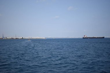 Kargo gemisi sakin mavi Akdeniz 'de, Anatalya' da. Akdeniz boyunca seyahat ederek, Antalya 'nın kayalık kıyılarını görebiliriz. Uzakta, kargo gemileri görünüyor..