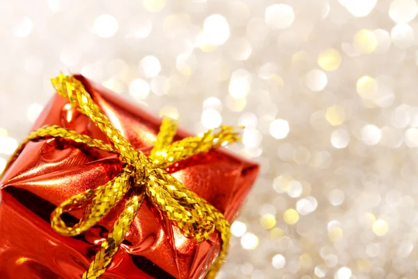 Caja de regalo roja de Navidad con lazo amarillo sobre fondo de plata y oro brillo — Foto de Stock