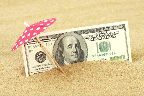 Geld Amerikaanse honderd dollarbiljetten in het strand zand onder rode en witte stippen zonnescherm — Stockfoto