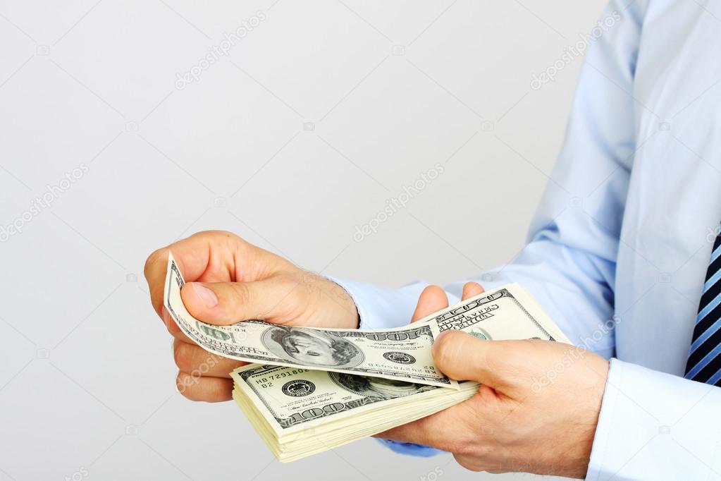 Men's hand holding money american hundred dollar bills. Hand of business man offering money.