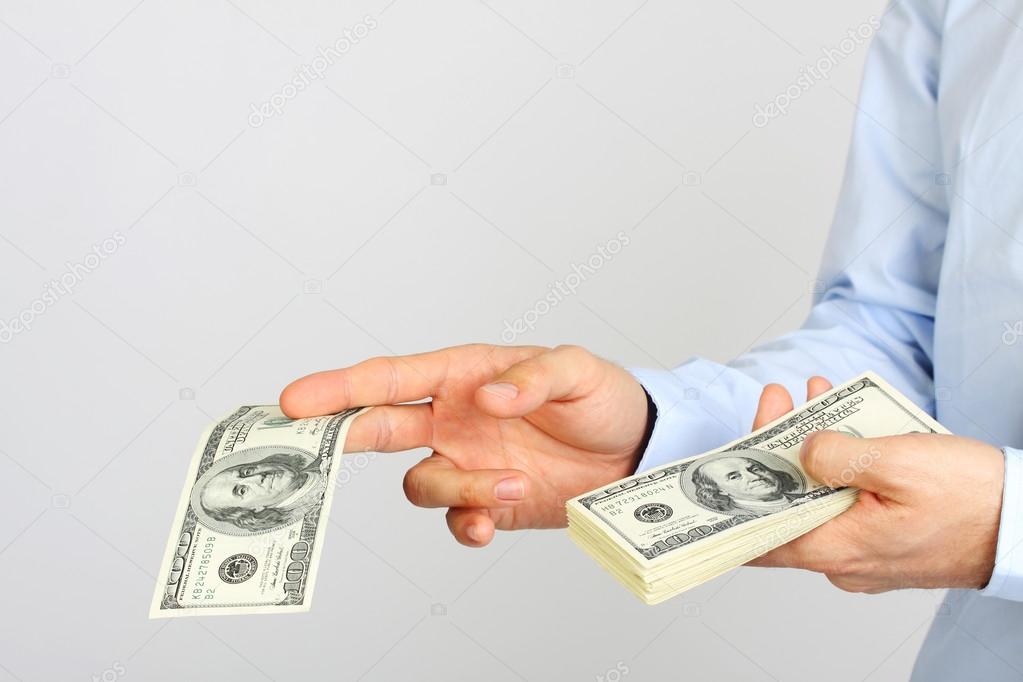 Men's hand holding money american hundred dollar bills. Hand of business man offering money.