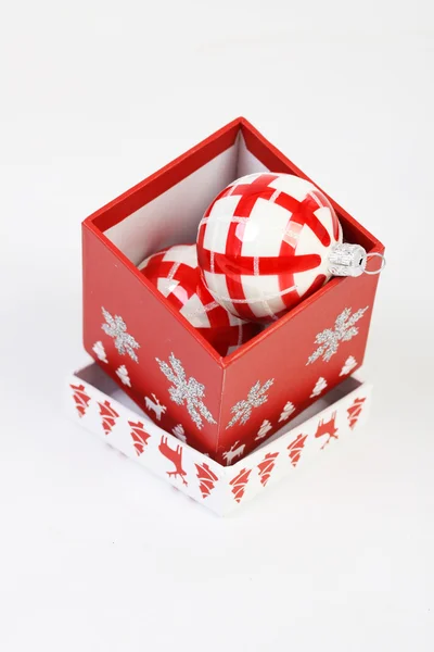 Красная рождественская коробка с красно-белыми рождественскими украшениями на белом фоне. Открываем рождественскую коробку с красно-белым шаром внутри . — стоковое фото