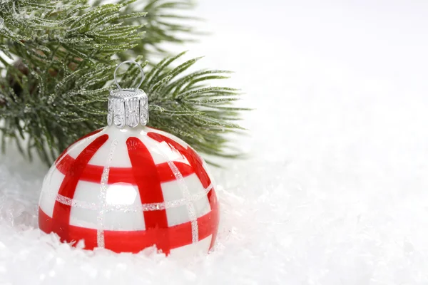 Röd och vit jul boll på snö och isbildning pine gren — Stockfoto