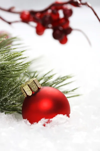 Red matt christmas ball on snow in front of icing on needles and red rowanberries - vertical — Stock Photo, Image