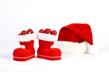 Santa Claus şapka ve bot kar önünde, beyaz arka plan üzerinde kırmızı ve mat Noel topları ile