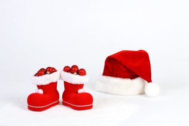 Santa Claus şapka ve bot kar önünde, beyaz arka plan üzerinde kırmızı ve mat Noel topları ile